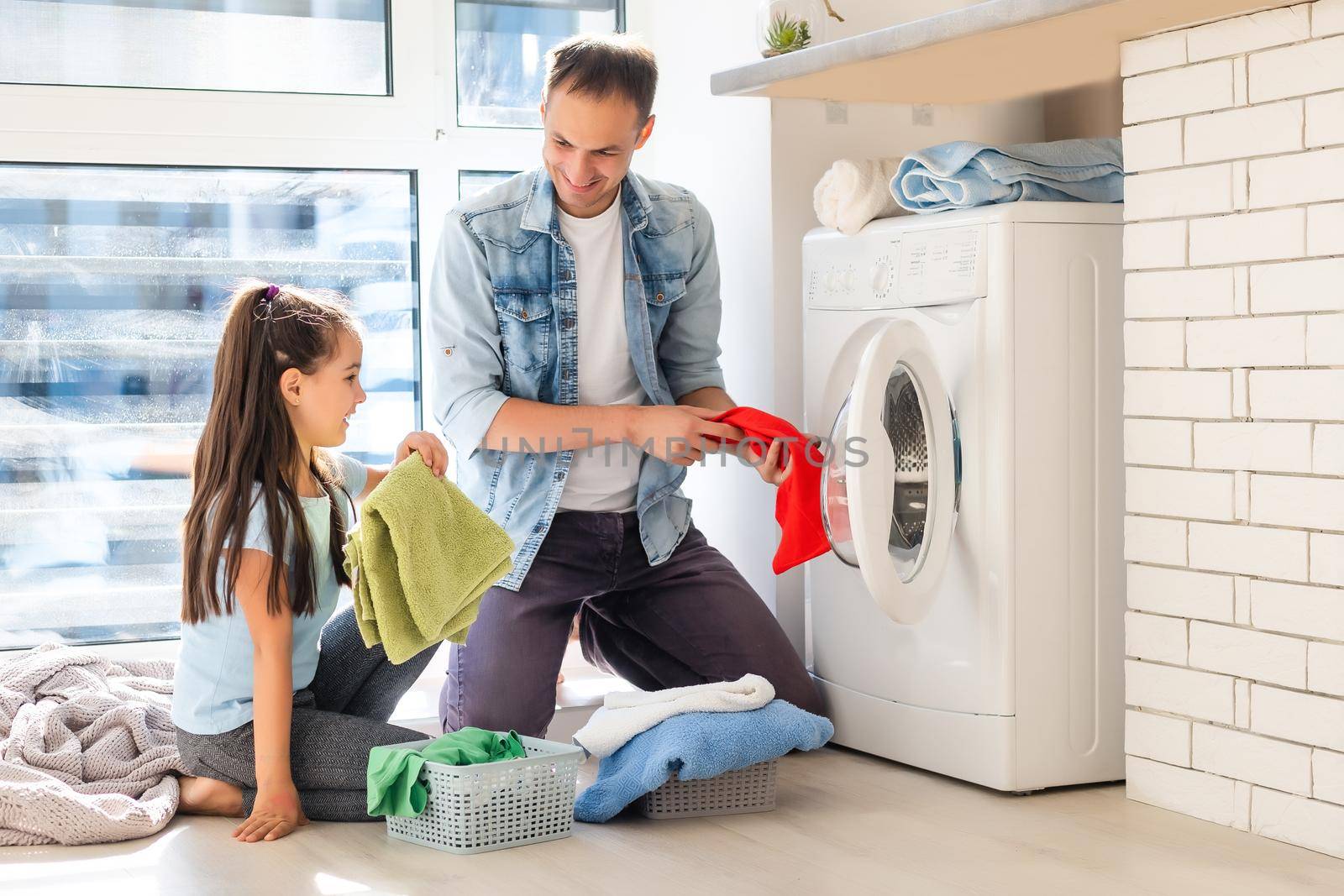 Happy family man father householder and child daughter in laundry with washing machine