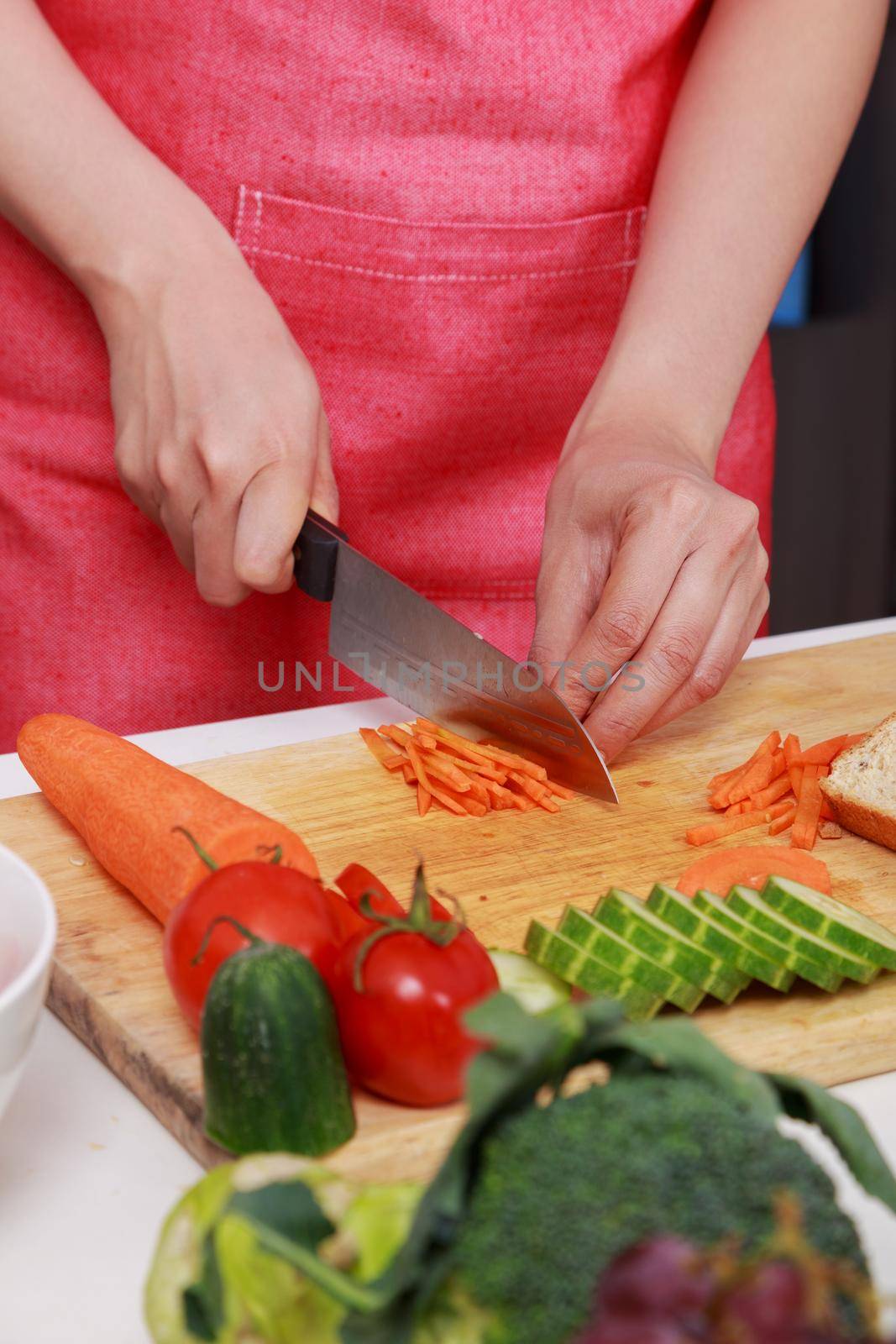 close up of hand cutting carrot on board in kitchen room