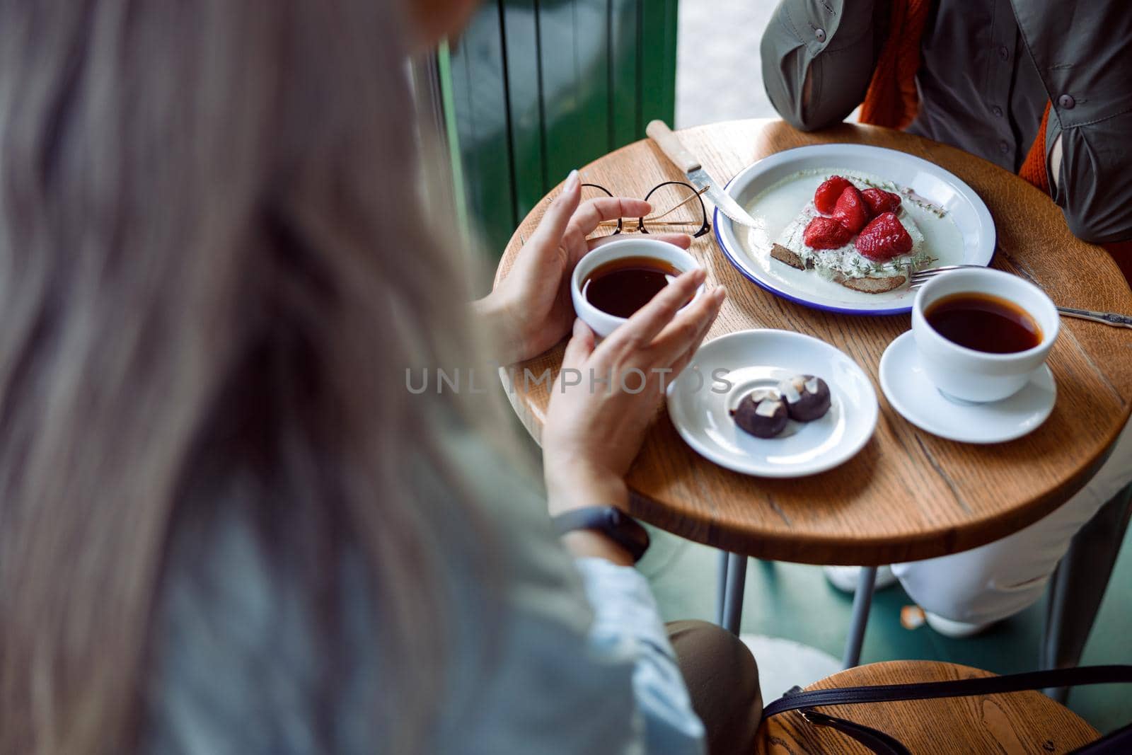Grey haired lady guest takes cup of coffee from small table spending time with friend in cozy cafe closeup. Long-time friendship