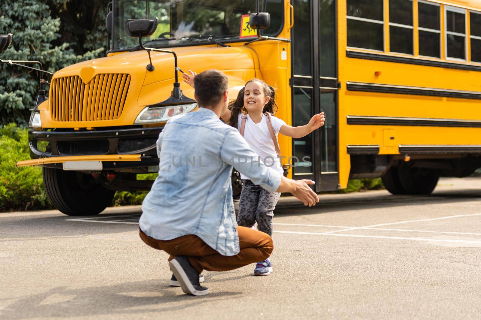 Father meeting little daughter coming out of school bus by Andelov13