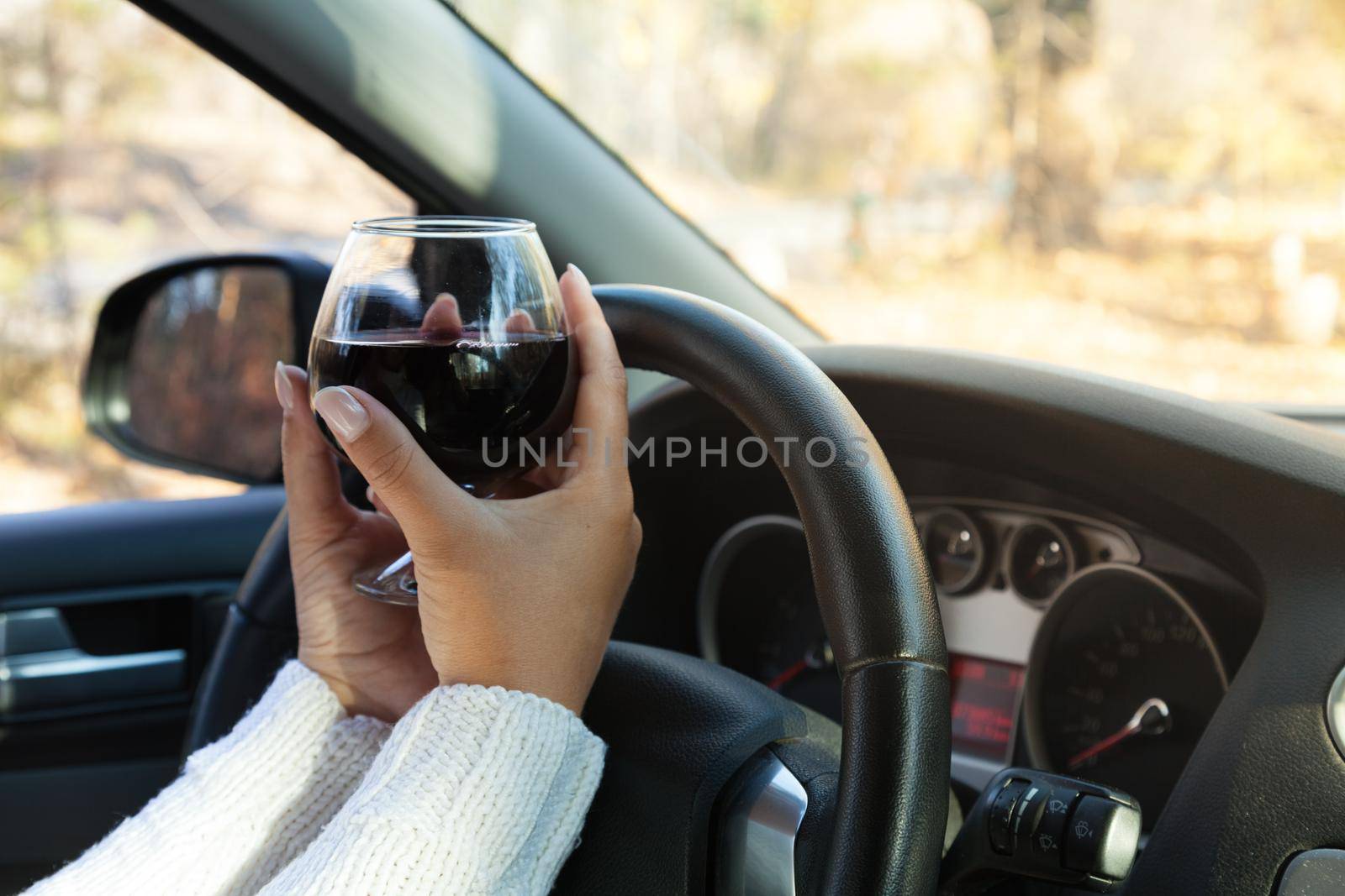 The girl at the wheel is drinking alcohol. Traffic safety threat by gordiza