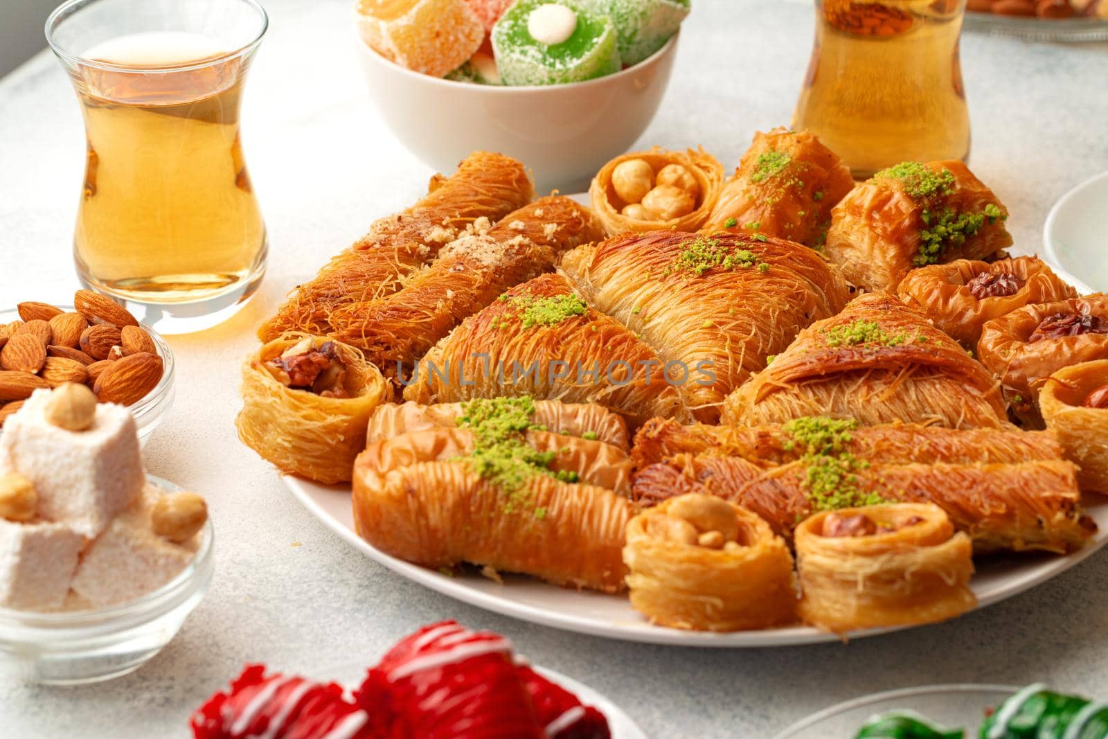 Various Turkish sweets and cup of tea on white textured background, close up