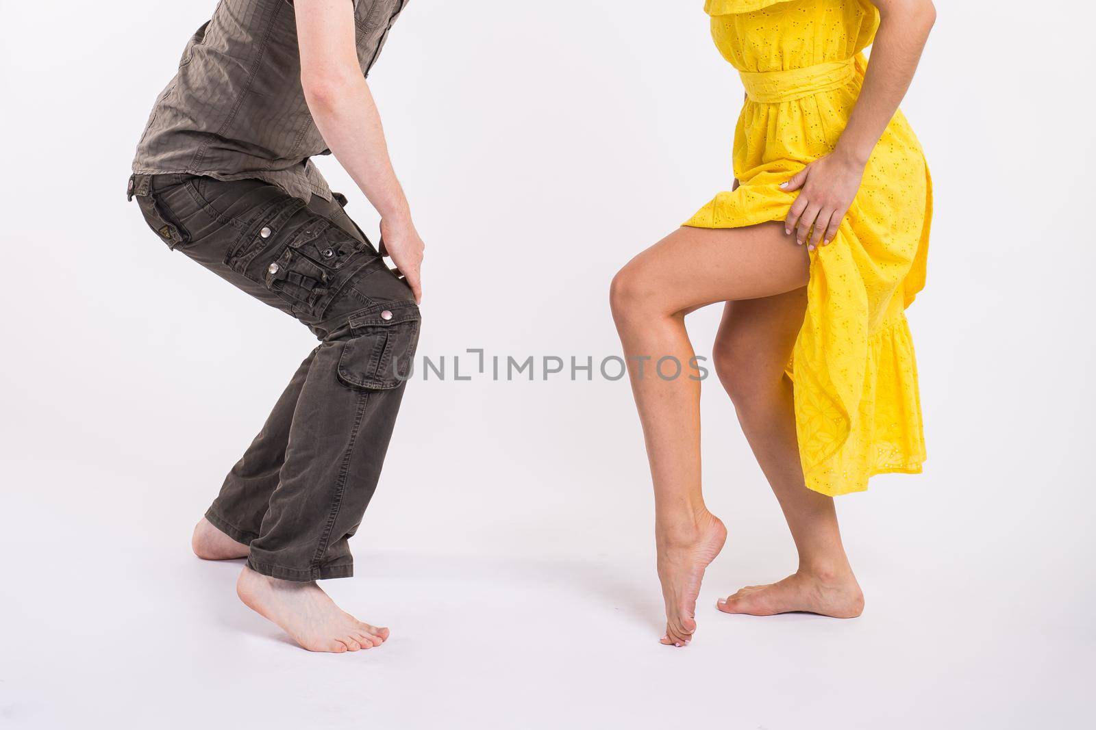 Couple dancing latin music. Bachata, merengue, salsa and kizomba. Close-up of legs elegance pose on white room. by Satura86