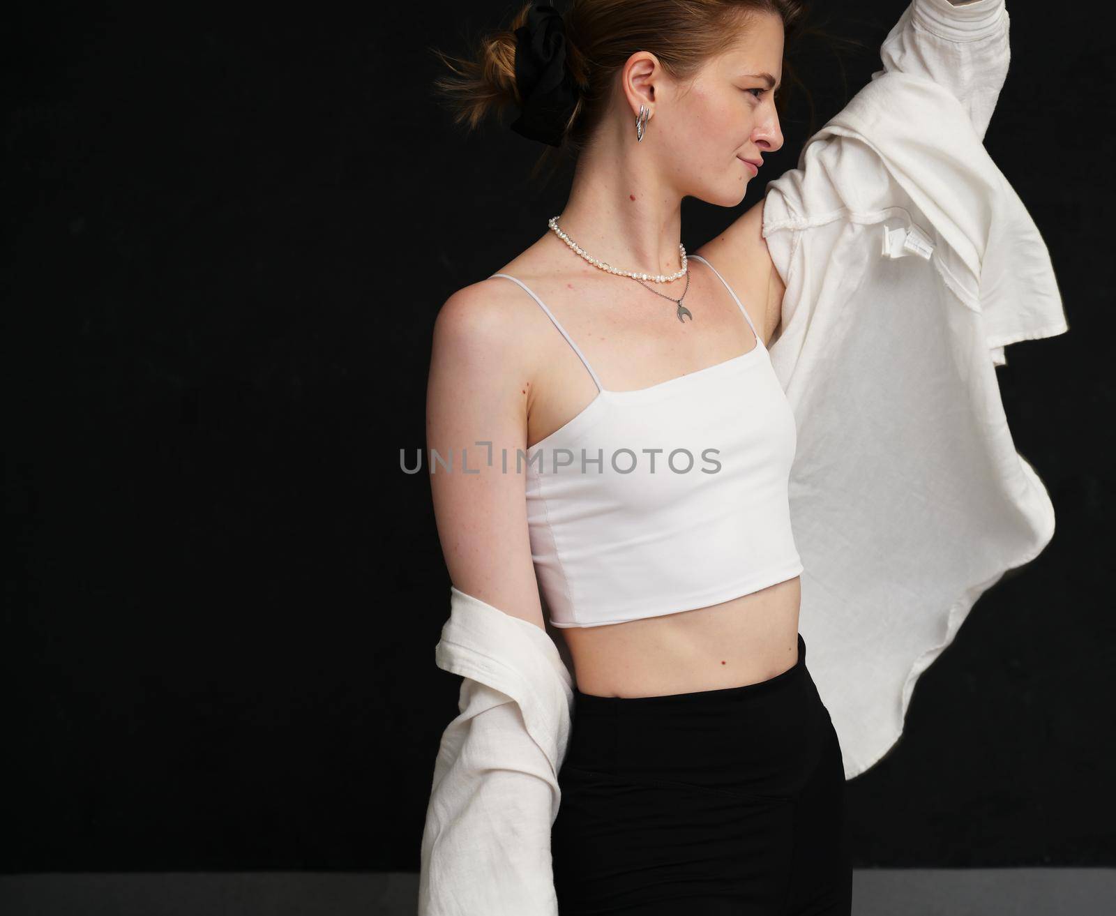 Caucasian girl in white blouse posing in studio on black background by chichaevstudio