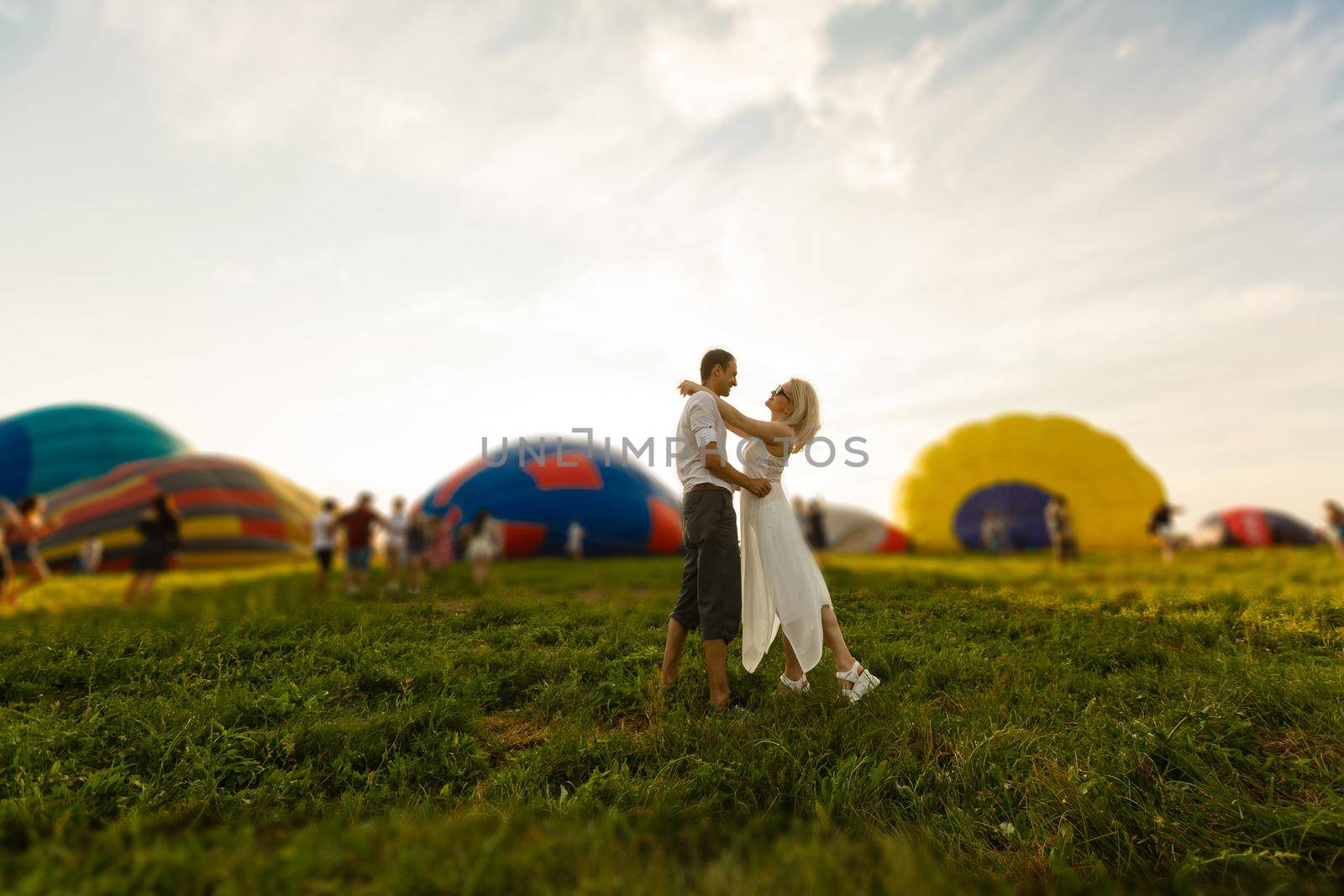 Beautiful romantic couple hugging at meadow. hot air balloon on a background by Andelov13
