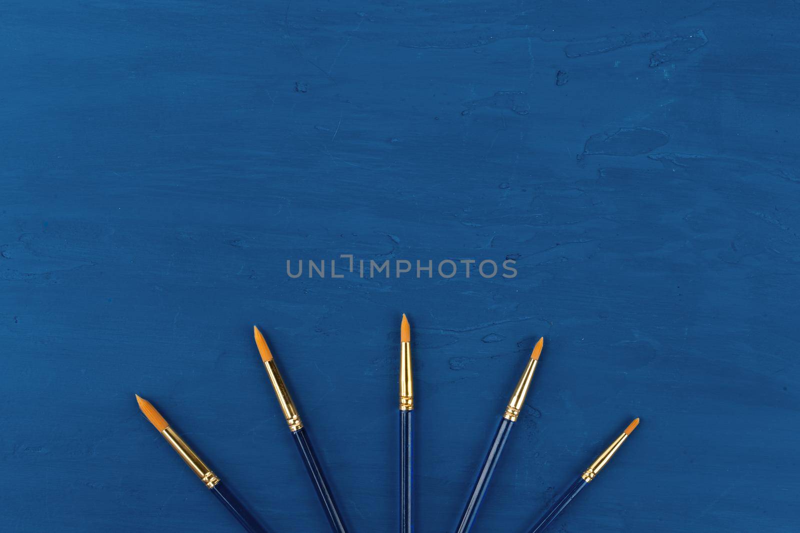 Blue paint brushes on classic blue background, view from above. High quality photo