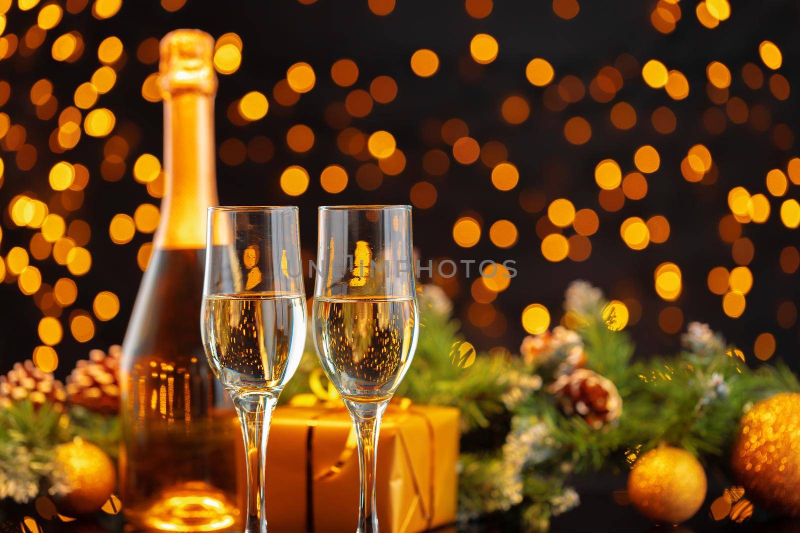 Champagne bottle and glasses on blurred lights background front view