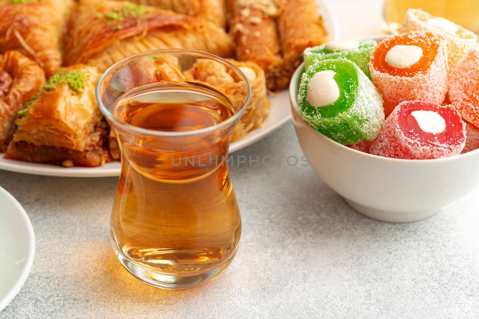Various Turkish sweets and cup of tea on white textured background, close up