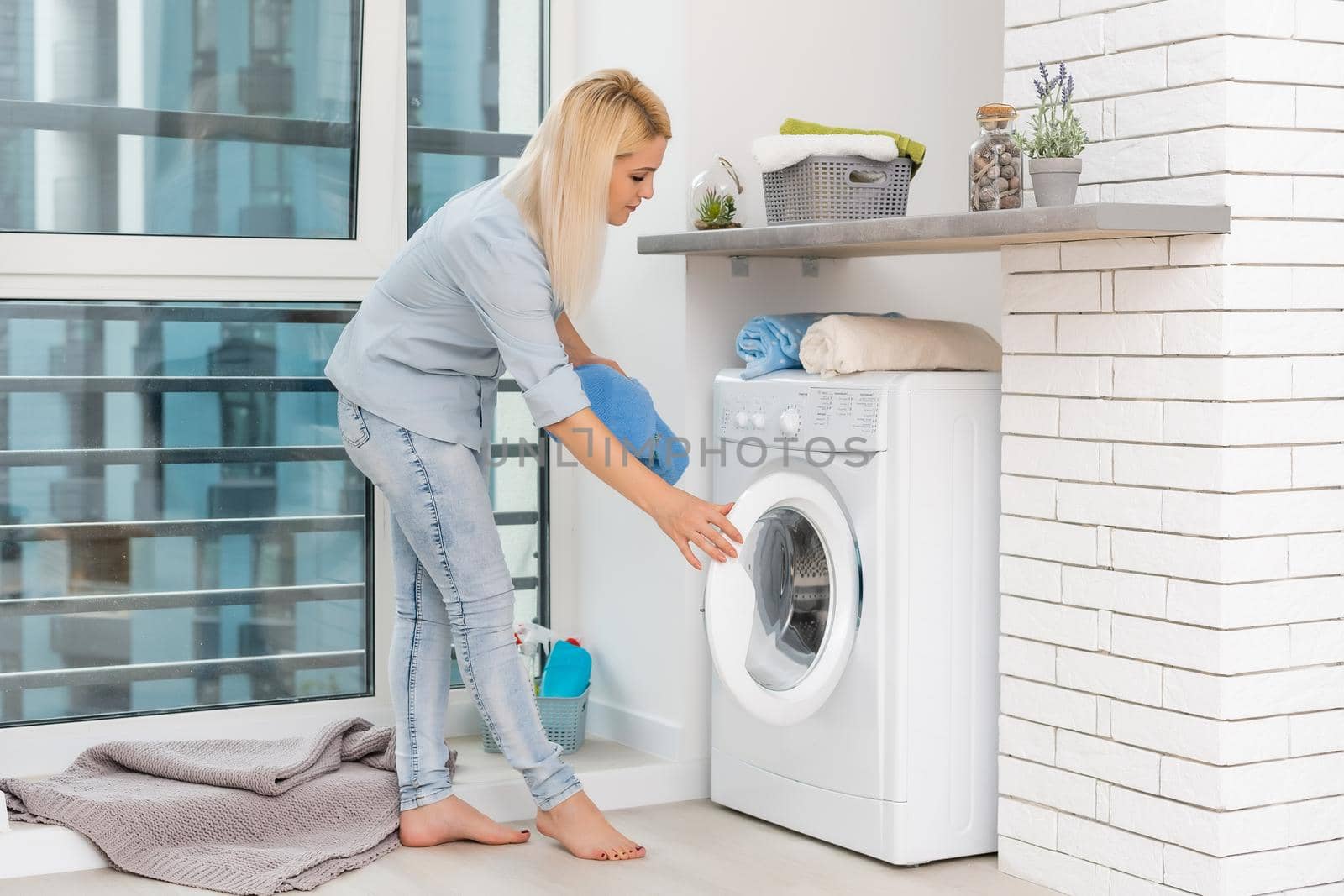A young housewife with washing machine and clothes. Washing day.
