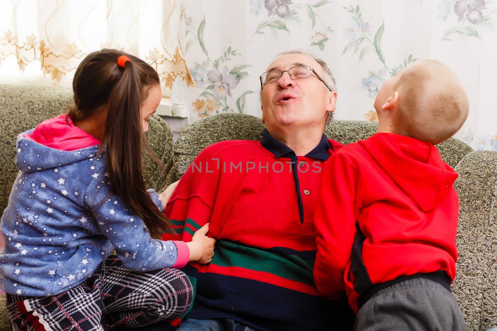Grandparents spending time with grandchildren on couch by Andelov13