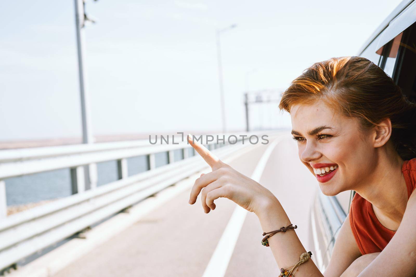 cheerful woman peeking out of the car window trip road travel. High quality photo