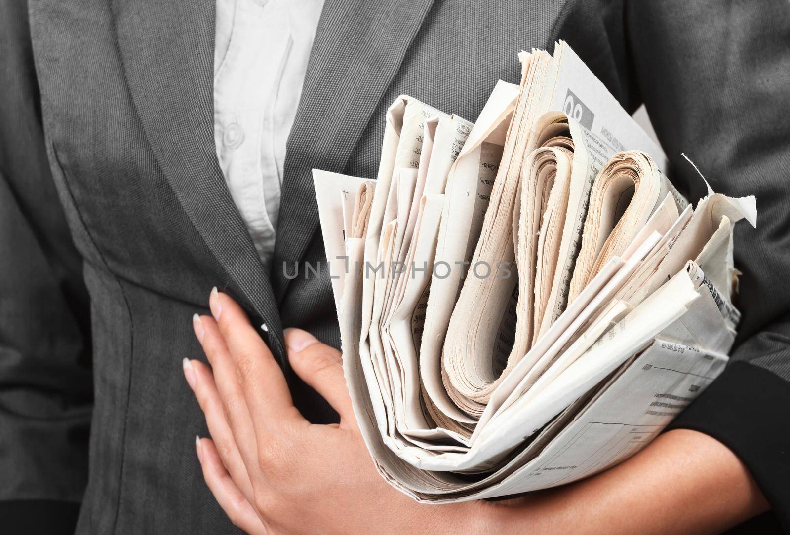 A woman in a jacket holds a stack of newspapers