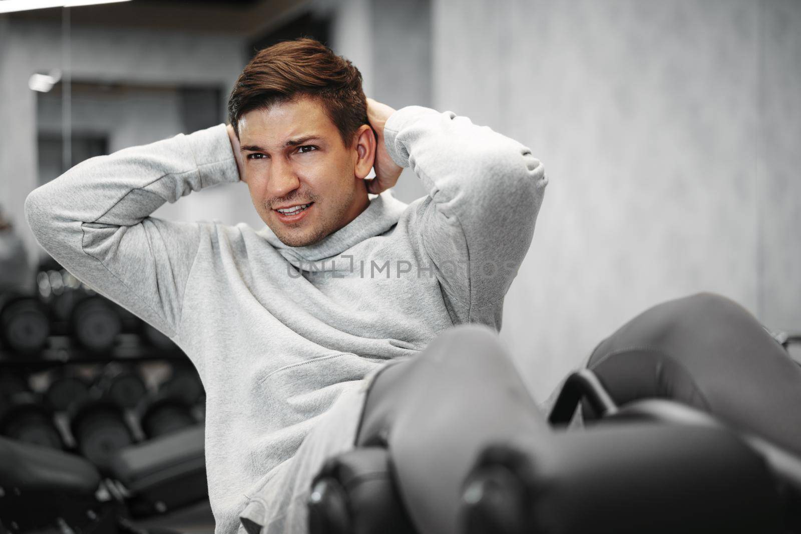 Young athlete doing abs exercises workout in modern gym, close up