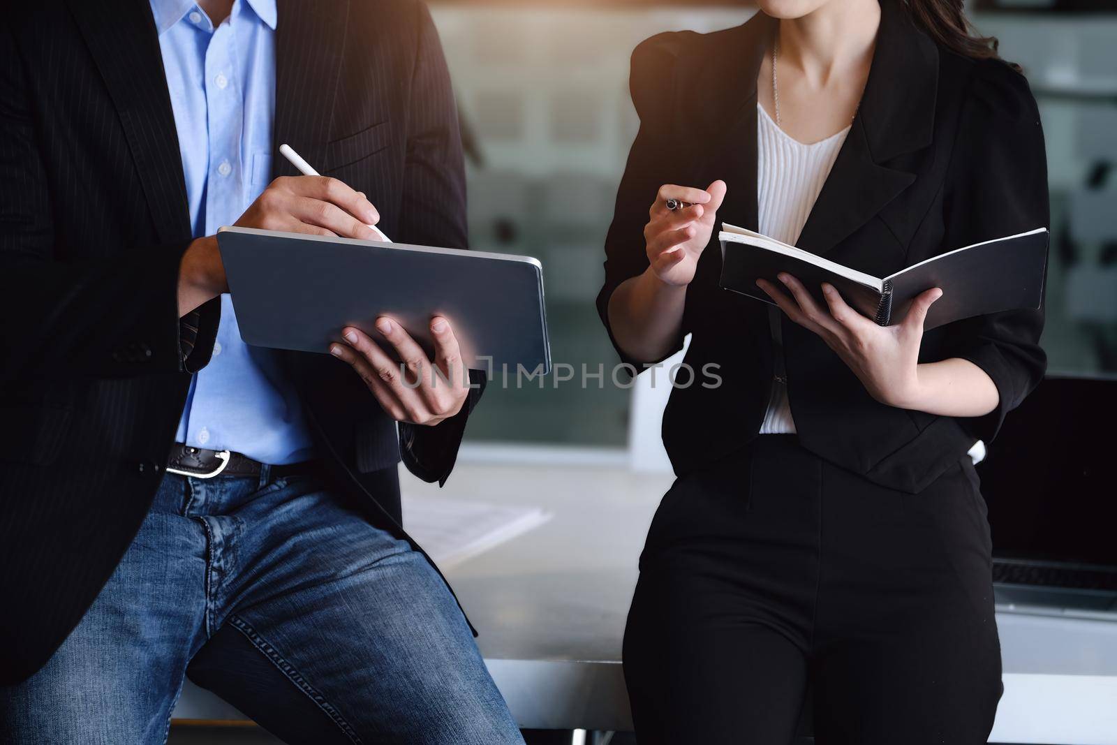 At the consultation, a male adviser uses a pen to point at a tablet to explain the profit restructuring to female business owners. by Manastrong