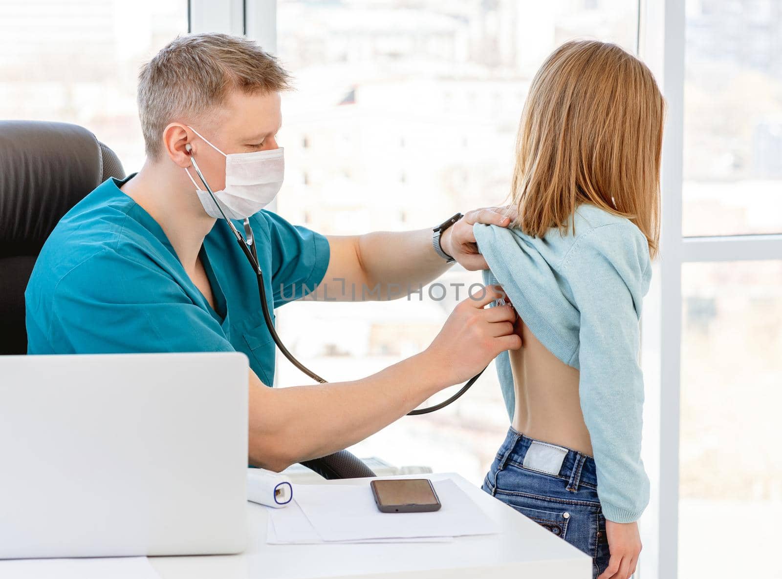 Doctor listening little girl by phonendoscope in clinic