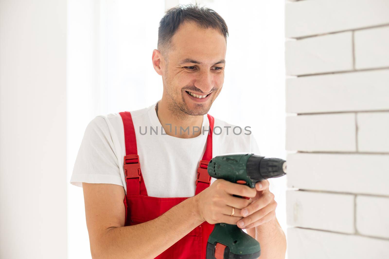 building, renovation, technology, electricity and people concept - builder with screwdriver fixing socket indoors
