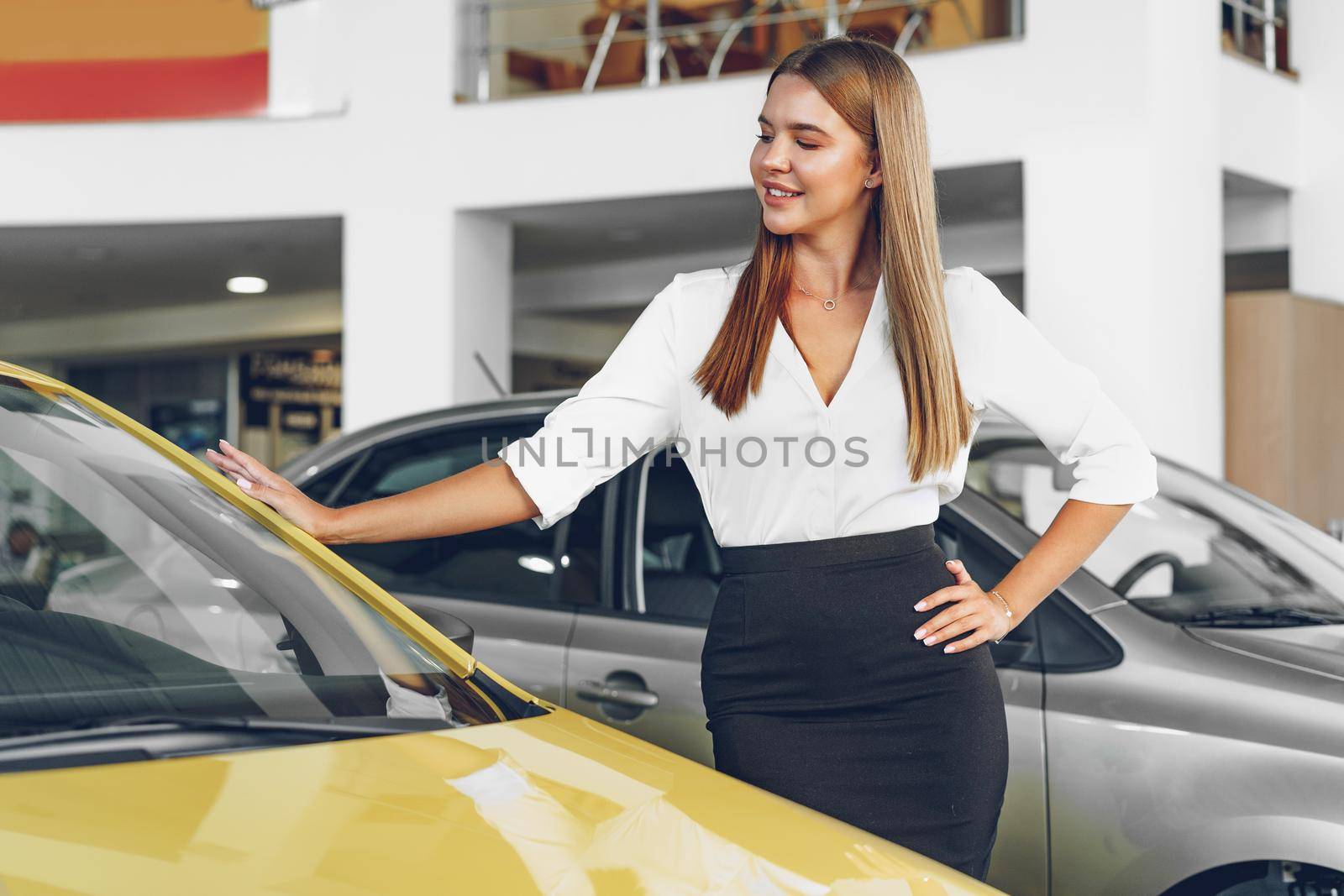 Young woman checking out a new car she is going to buy in car salon