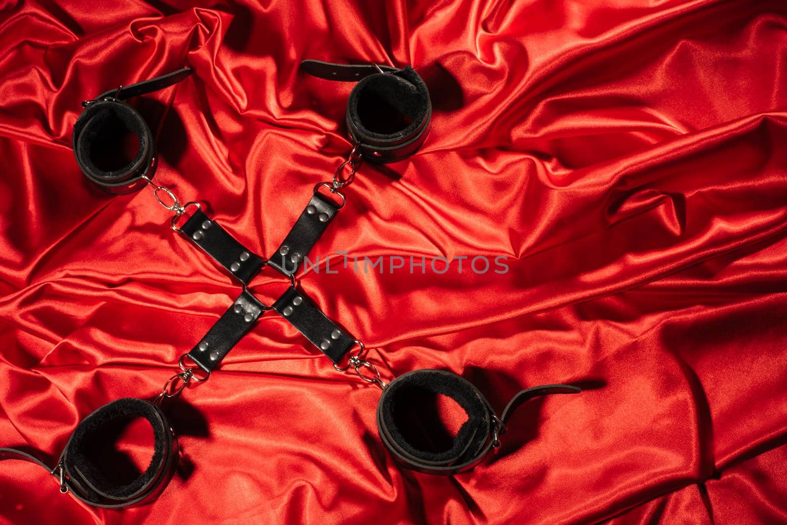 Top view of bdsm outfit. Bondage crossed on the red linen. Adult sex games. Kinky lifestyle. - image