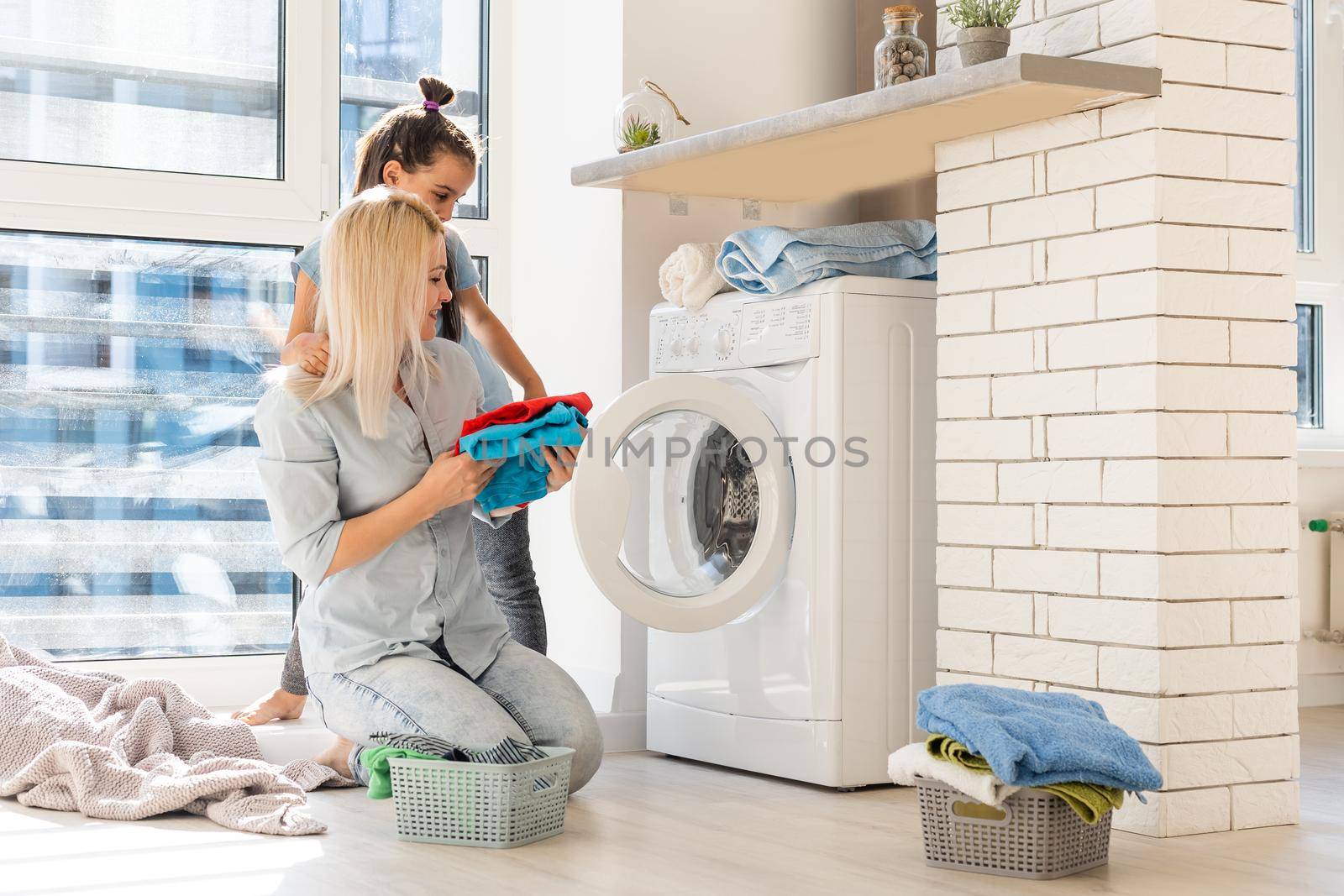 family mother and child girl little helper in laundry room near washing machine and dirty clothes by Andelov13