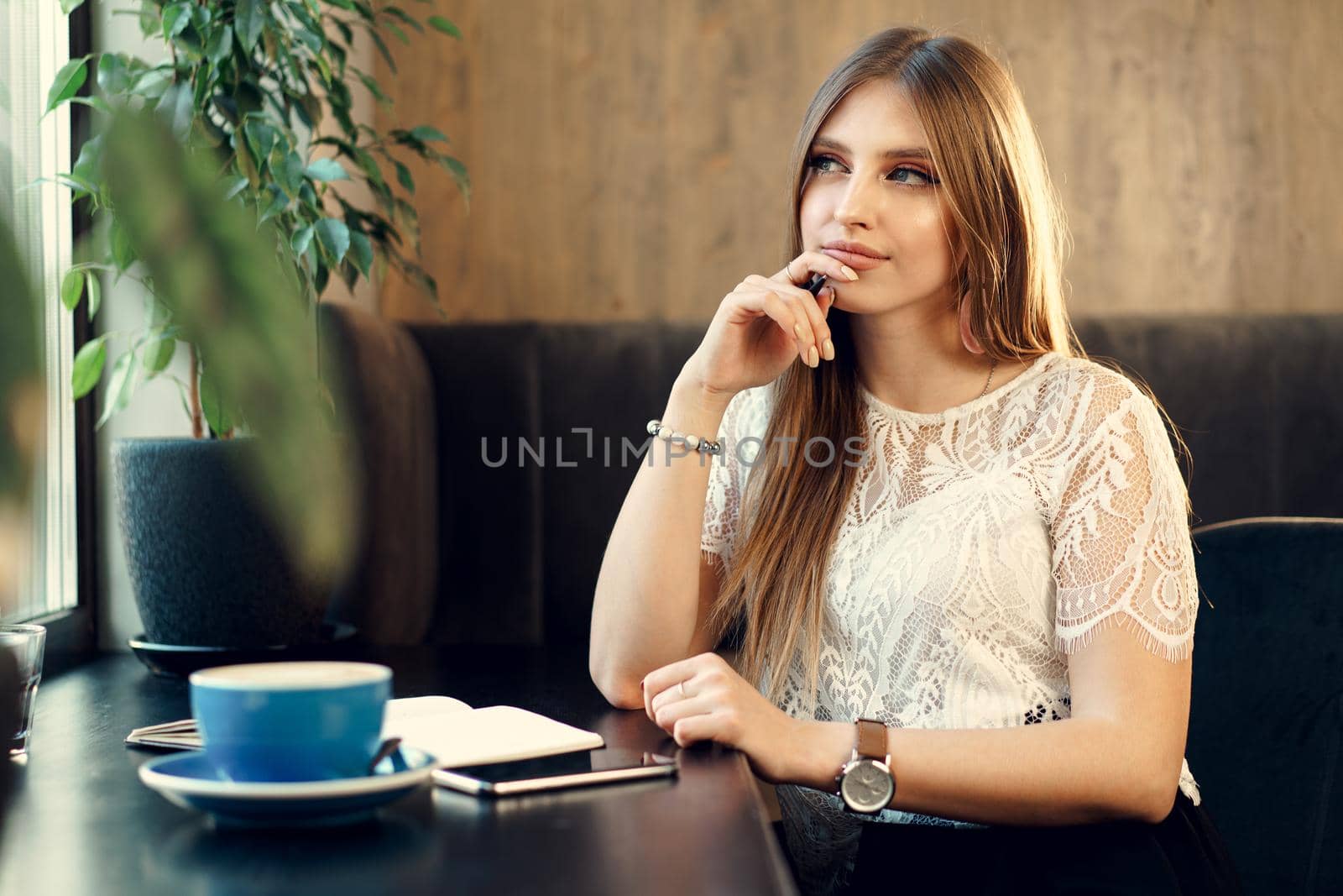 Young business woman sitting at the table in a coffee shop and making notes. Close up.