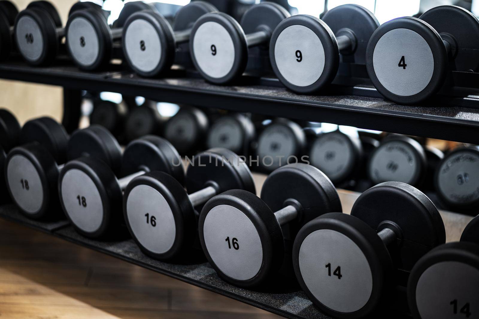 Close up photo of new dumbbells on a rack in a gym