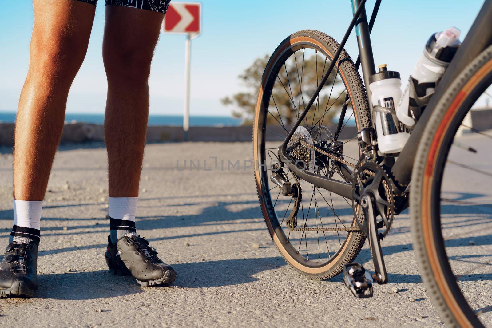 Cyclist man feet and bike wheel on coastal road close up
