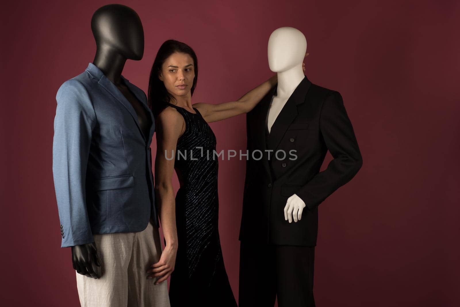 A young girl with problematic skin suffers from loneliness in a society of stylish manikins on ruby background.