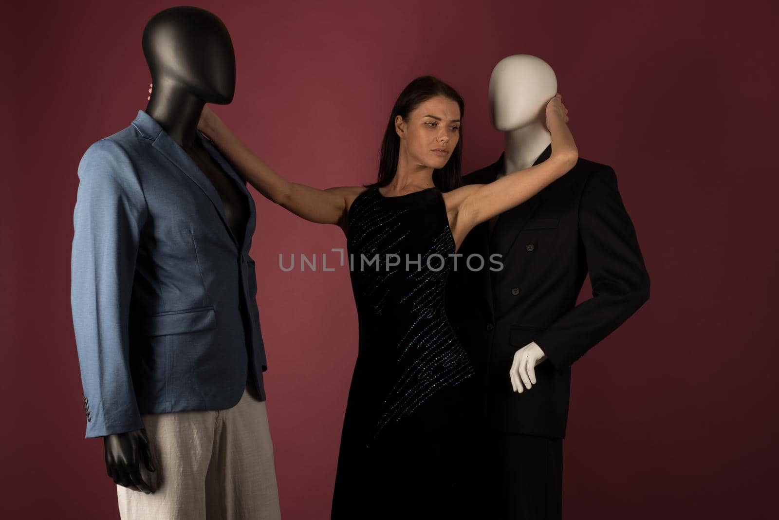 A young girl with problematic skin suffers from loneliness in a society of stylish manikins on ruby background.