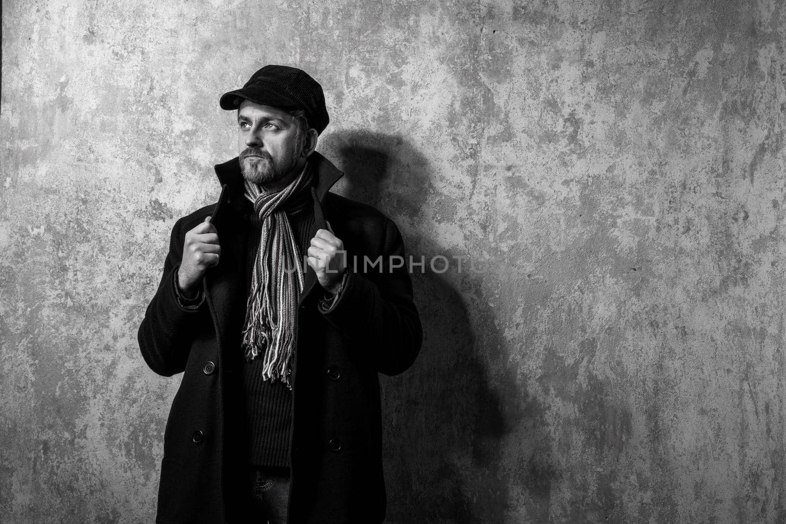 image of a caucasian man with grungy blond hair dressed warmly in a stylish black trench coat and a funky hat and scarf for the cold winter