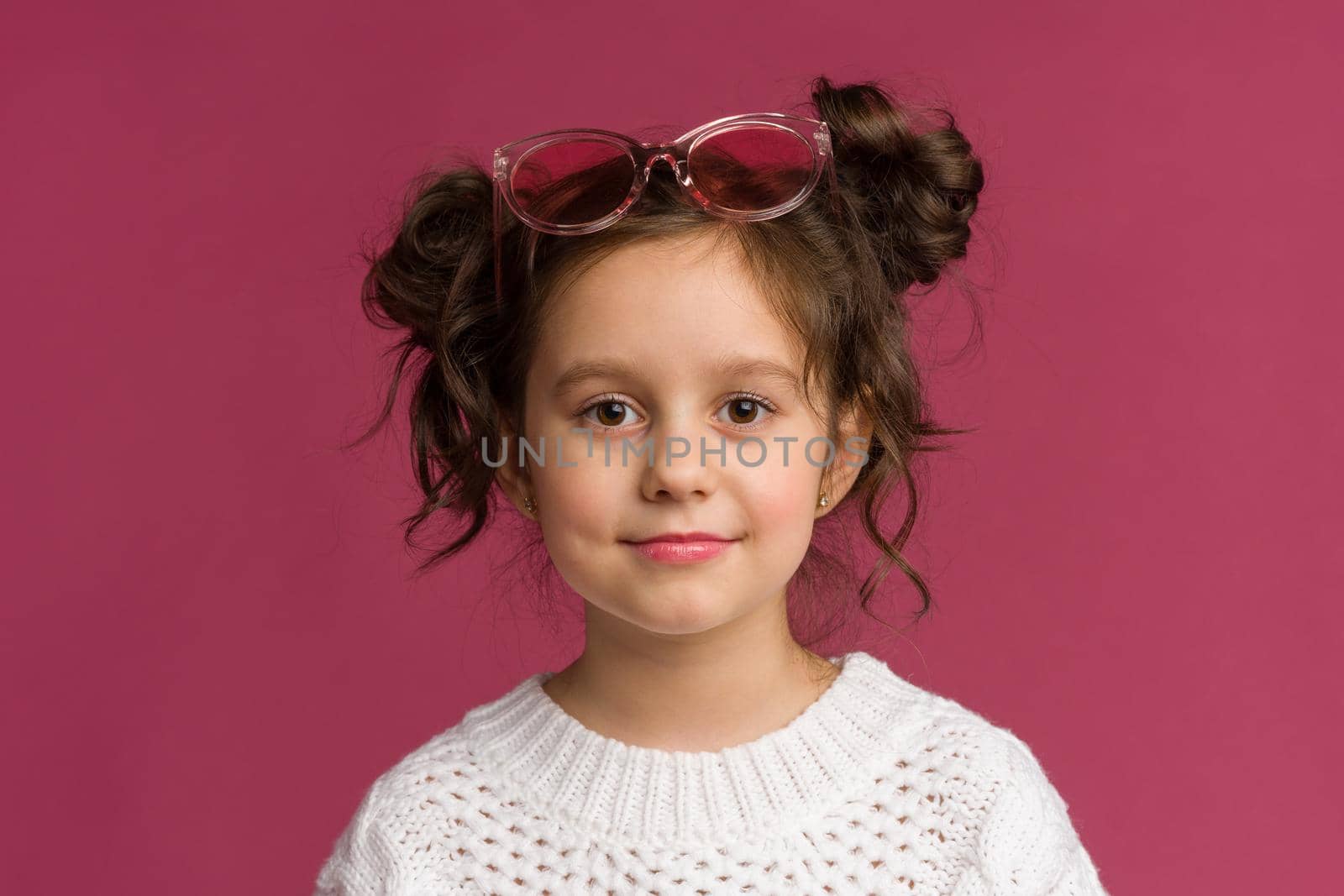 Photo of smiling little girl child isolated over pink background. Looking camera.