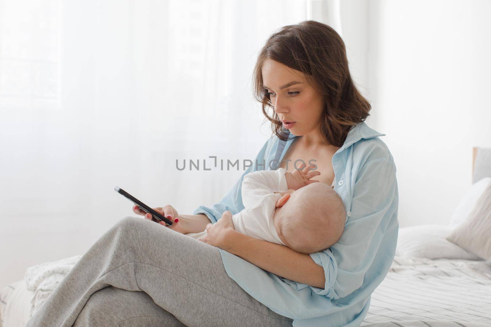 Woman using smartphone while breastfeeding by Demkat