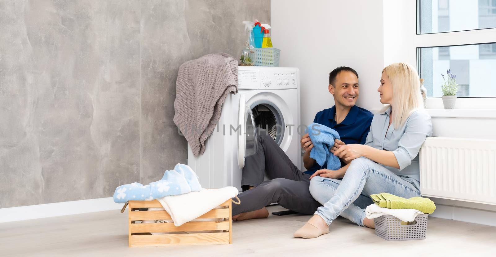 Young couple doing housework. Laundry room in new apartment.