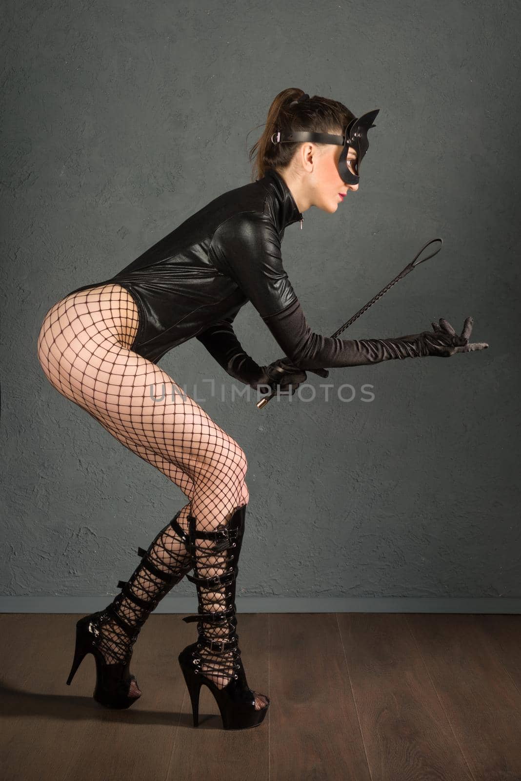 Beautiful dominant brunette mistress girl in latex body, gloves and bdsm black leather fetish cat mask posing with riding crop by zartarn