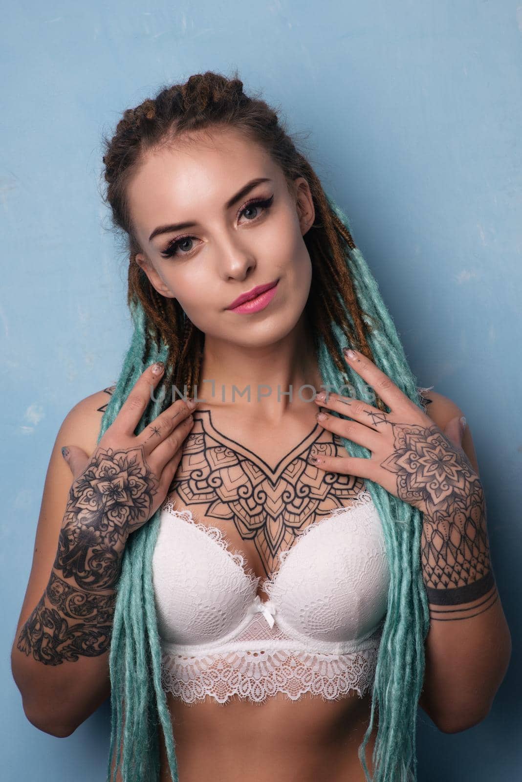 Sexual blonde girl with fascinating dreadlocks posing by the grunge wall. Pin-up style.