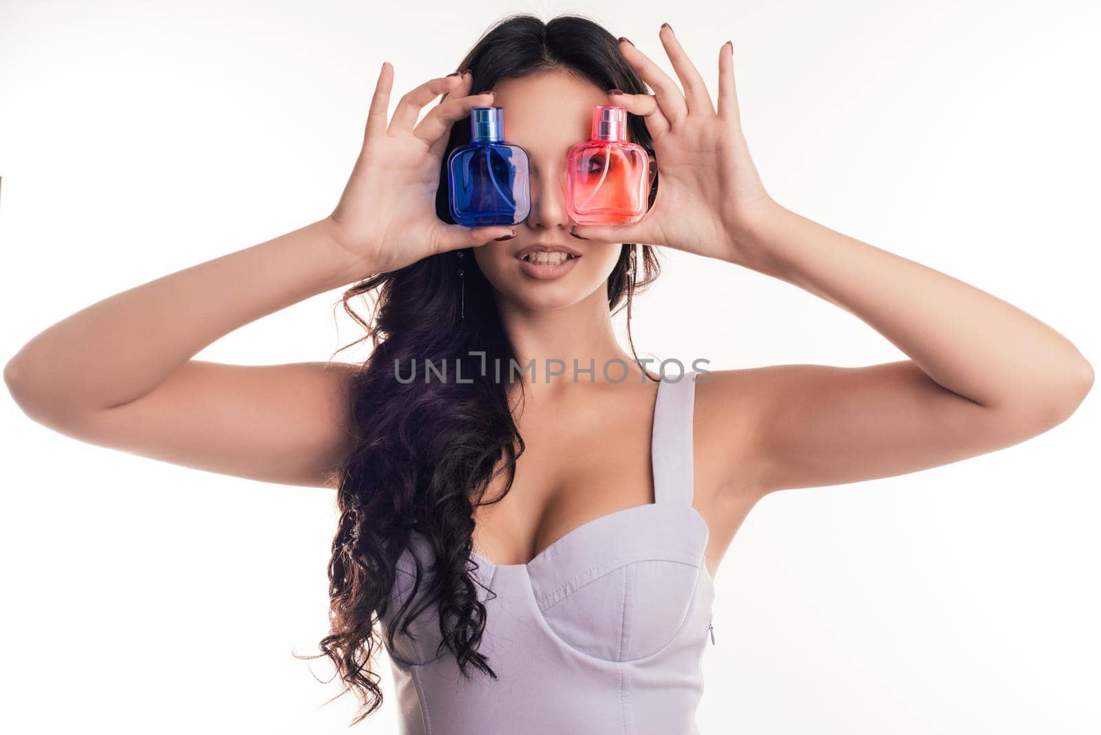 Portrait of attractive girl closes her eyes with perfume bottles.