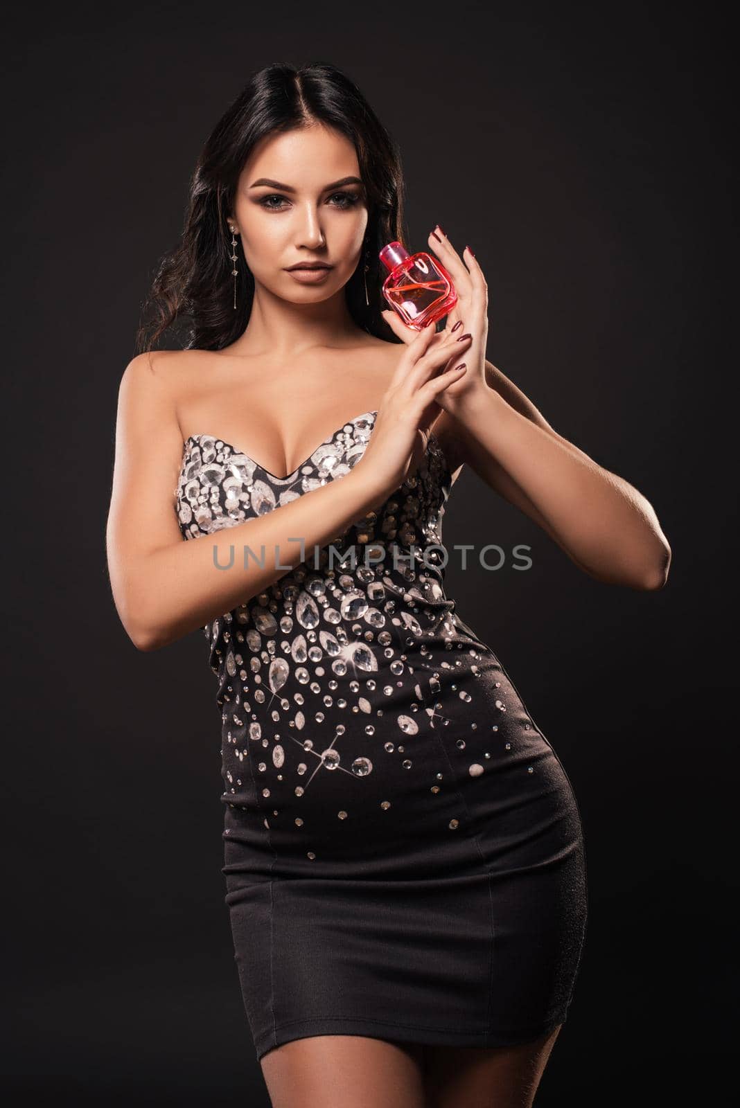Beautiful woman with perfume bottle on gray background by zartarn