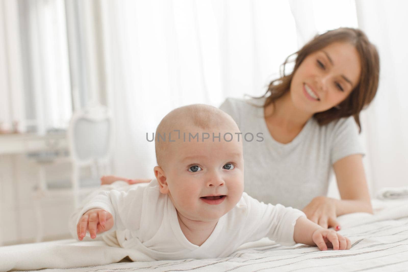 Mother and baby playing and smiling on bed by Demkat