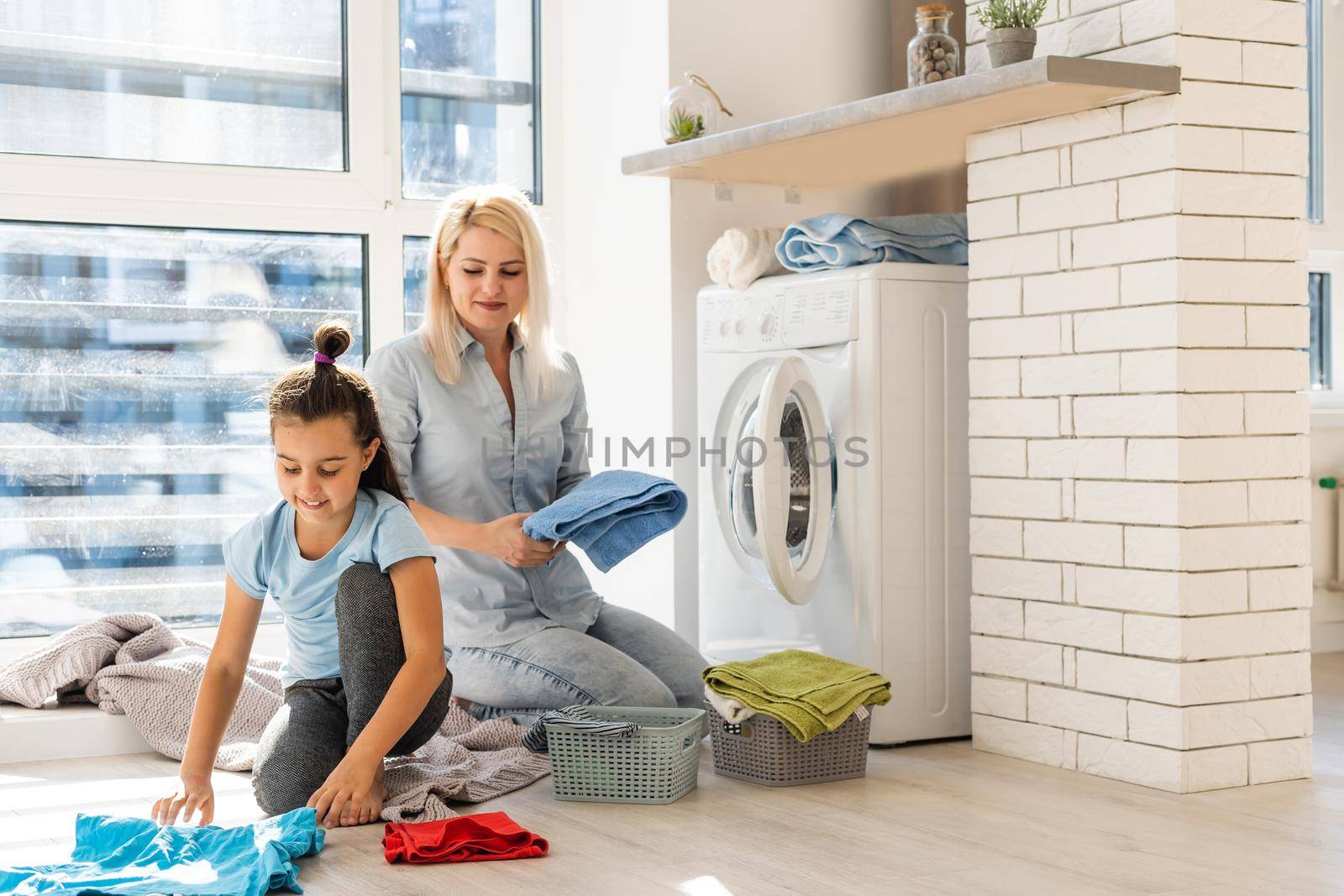 Young housewife and little girl doing laundry together by Andelov13
