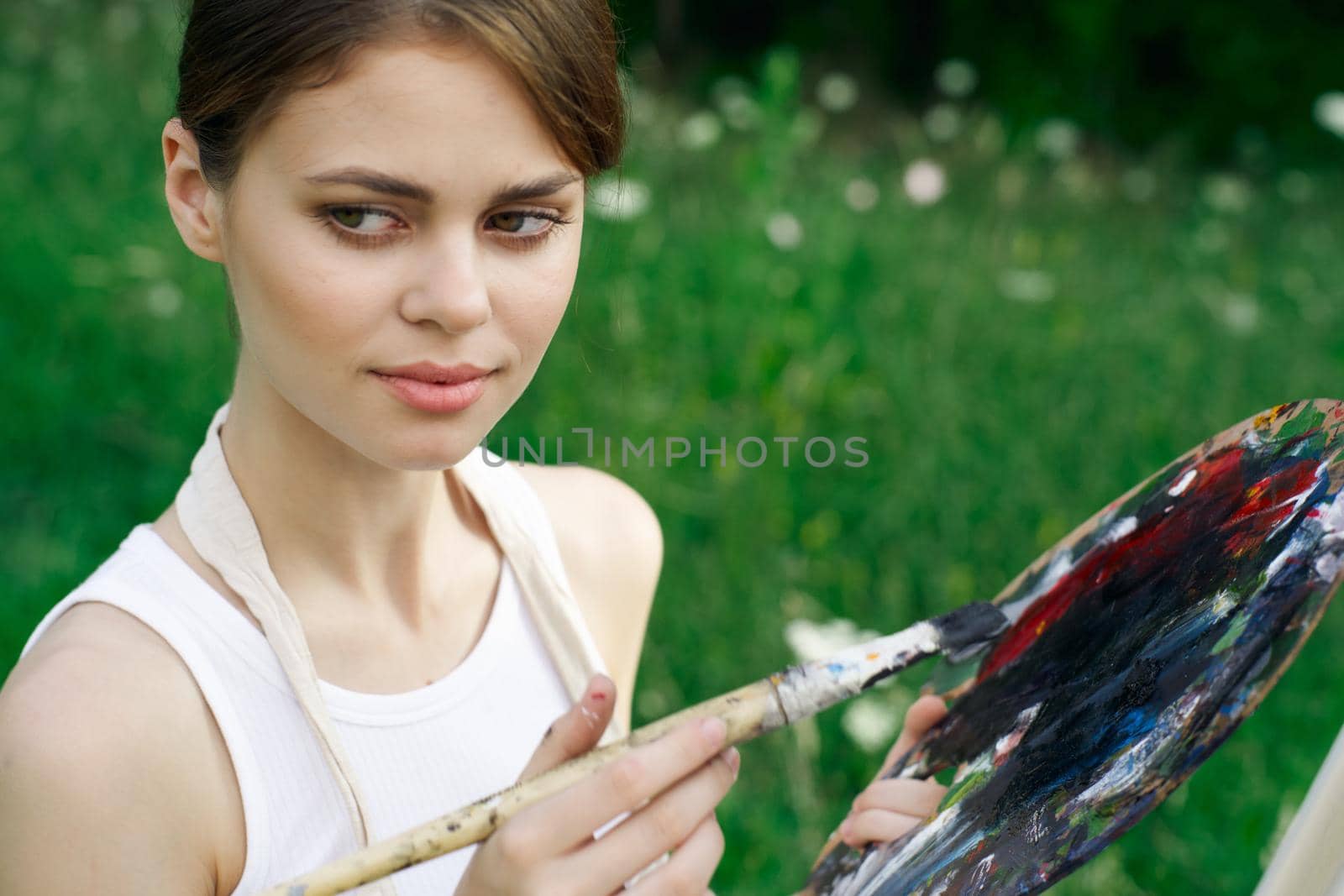 woman artist in white dress paint palette drawing close-up. High quality photo