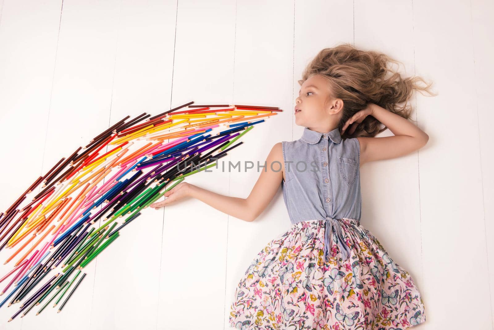 A nice young girl lies on the floor and blows a stream of colored pencils by zartarn