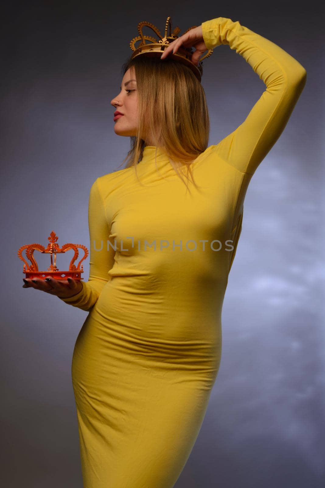 beautiful girl in yellow evening dress holds one crown in his hand a second on his head by zartarn