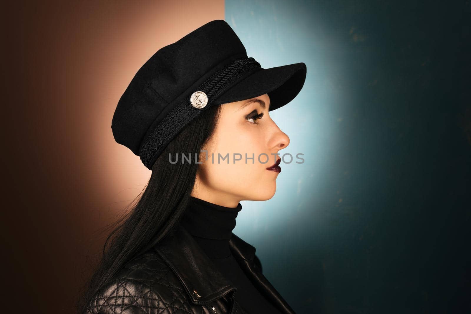 Beautiful young make-up model profile in cap with long hair style posing on dark black background by zartarn