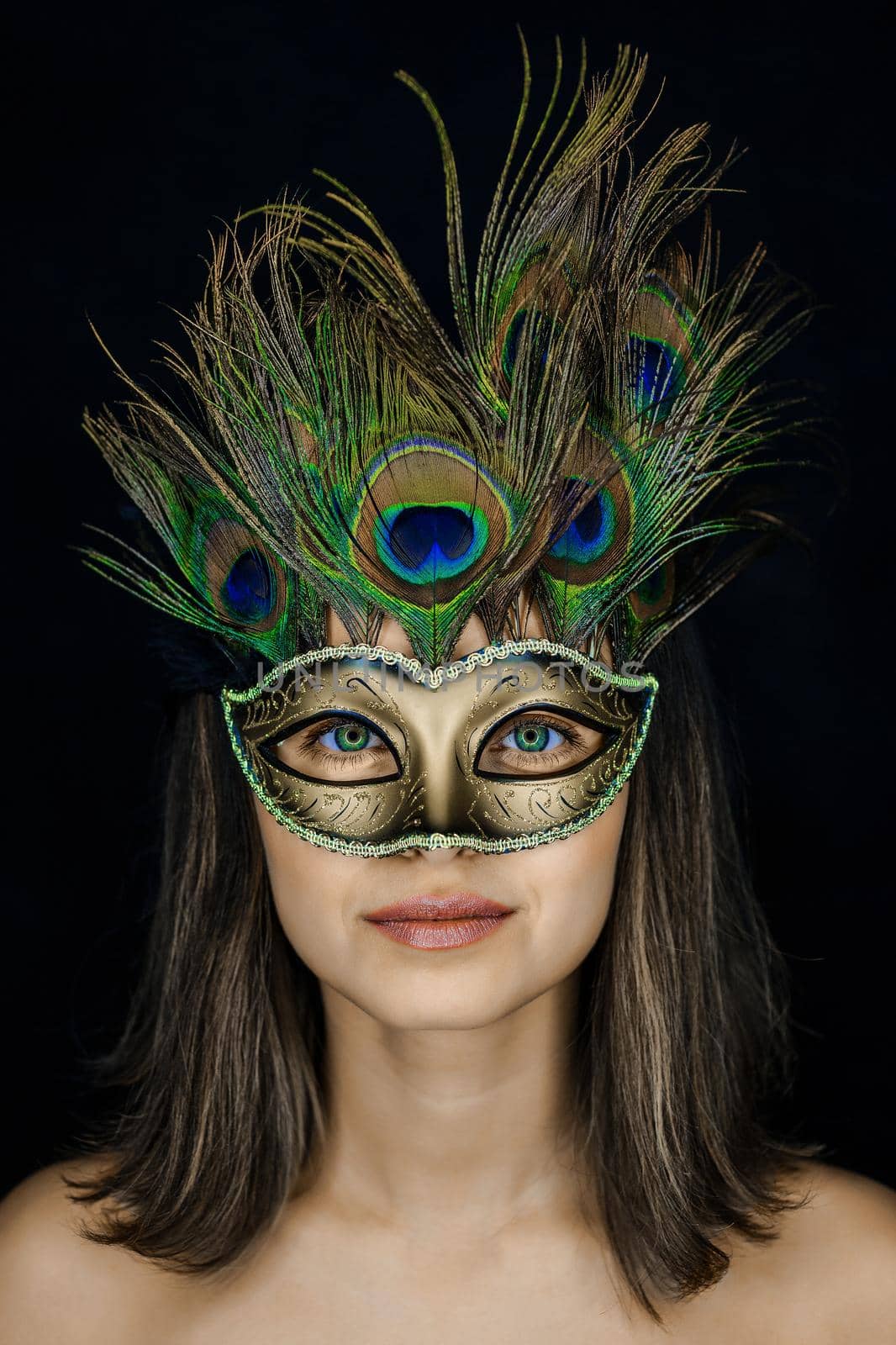 Close-up portrait of a young beautiful woman in a Venetian masquerade mask on a dark background. ring flash