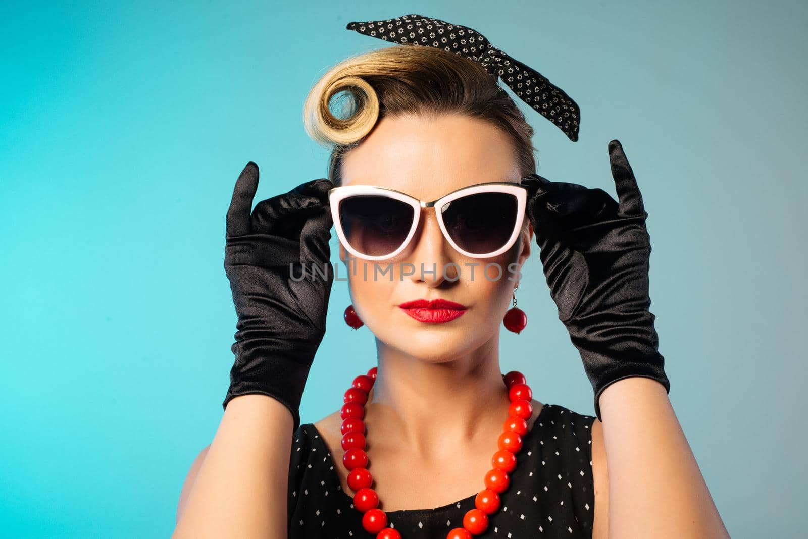 Beautiful young woman with glamour red lips wearing sunglasses and fancy plastic earrings, pinup style