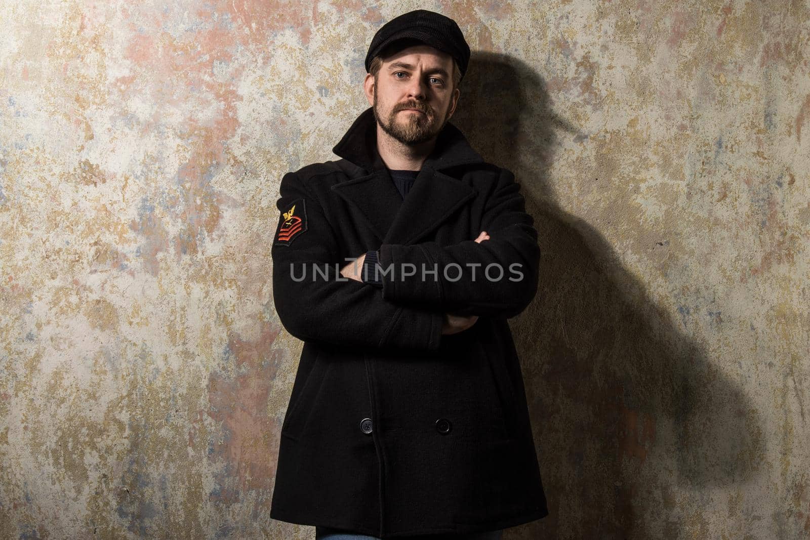 image of a caucasian man with grungy blond hair dressed warmly in a stylish black trench coat and a funky hat and scarf for the cold winter.