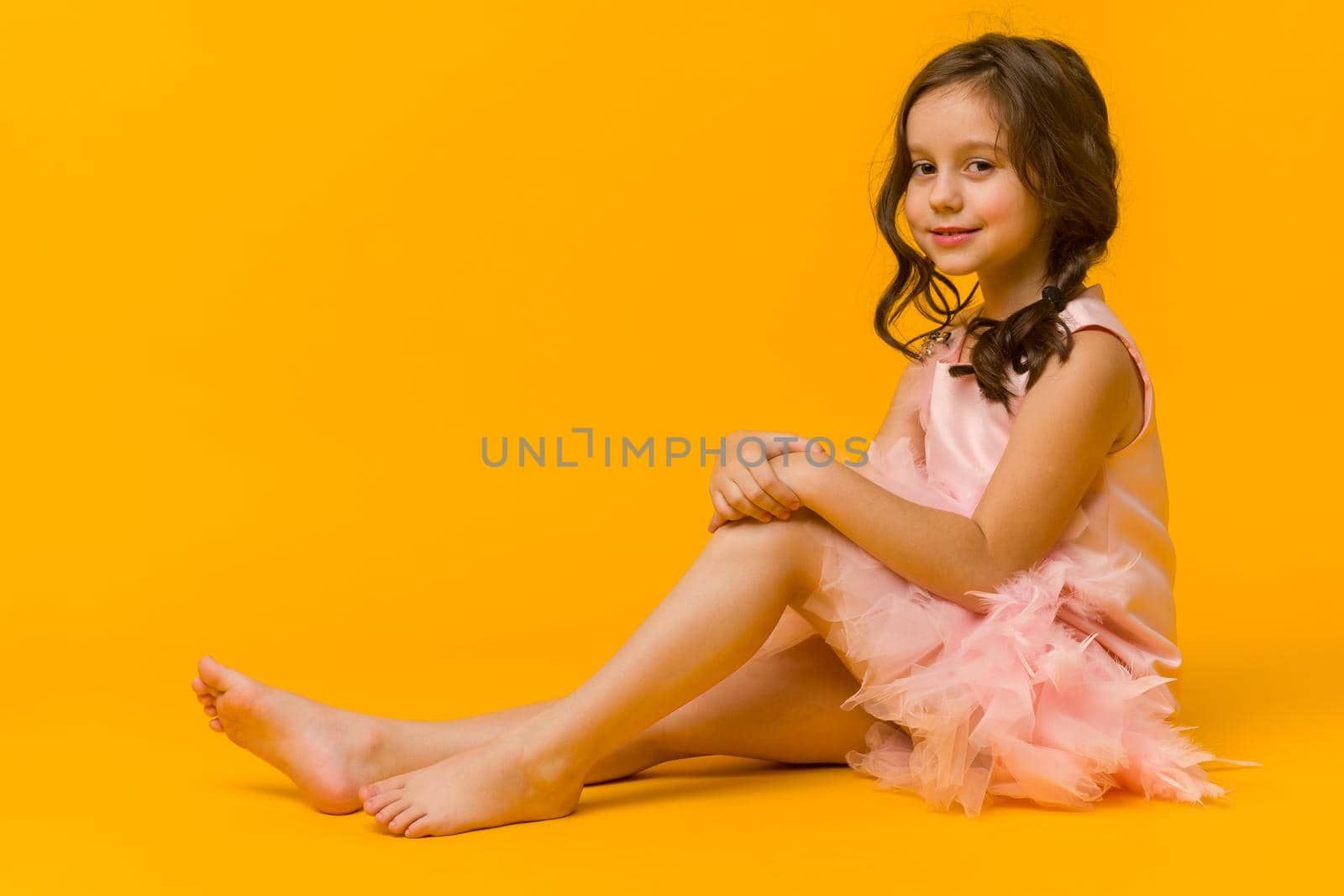 Photo of smiling little girl child isolated over yellow background. Looking camera.