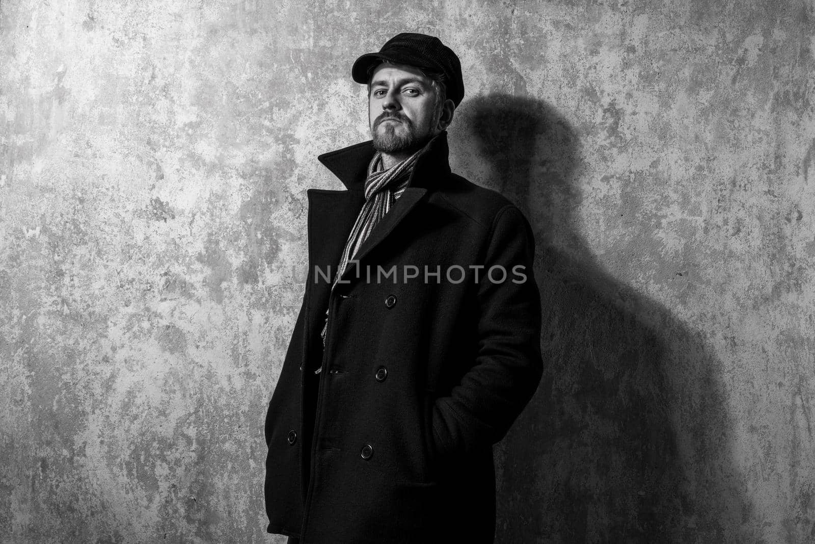 image of a caucasian man with grungy blond hair dressed warmly in a stylish black trench coat and a funky hat and scarf for the cold winter