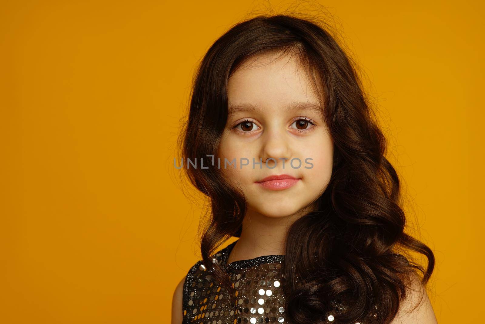 Photo of smiling little girl child isolated over yellow background. Looking camera.