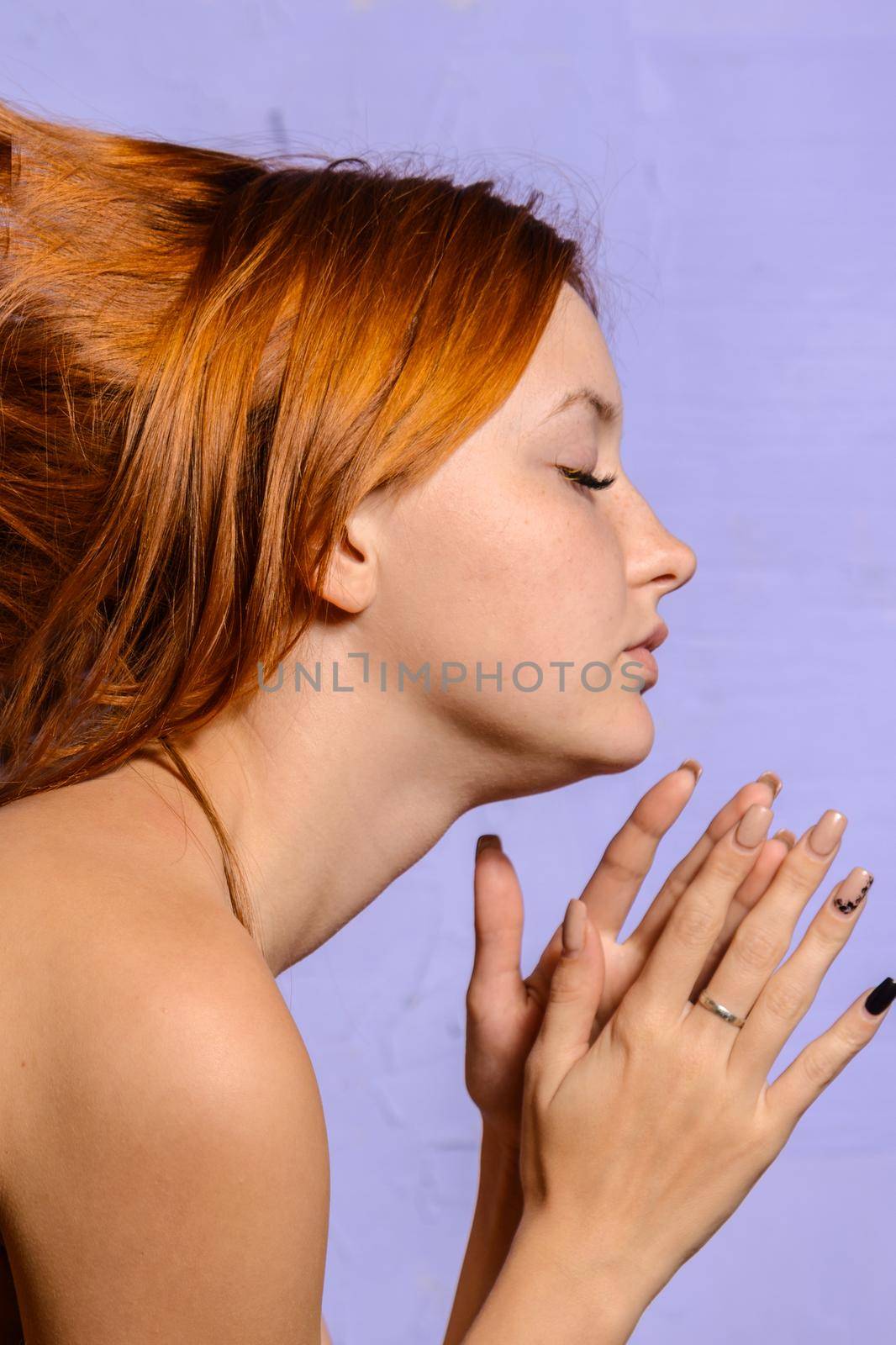 Attractive red-haired girl clasped her hands in prayer. portrait in profile