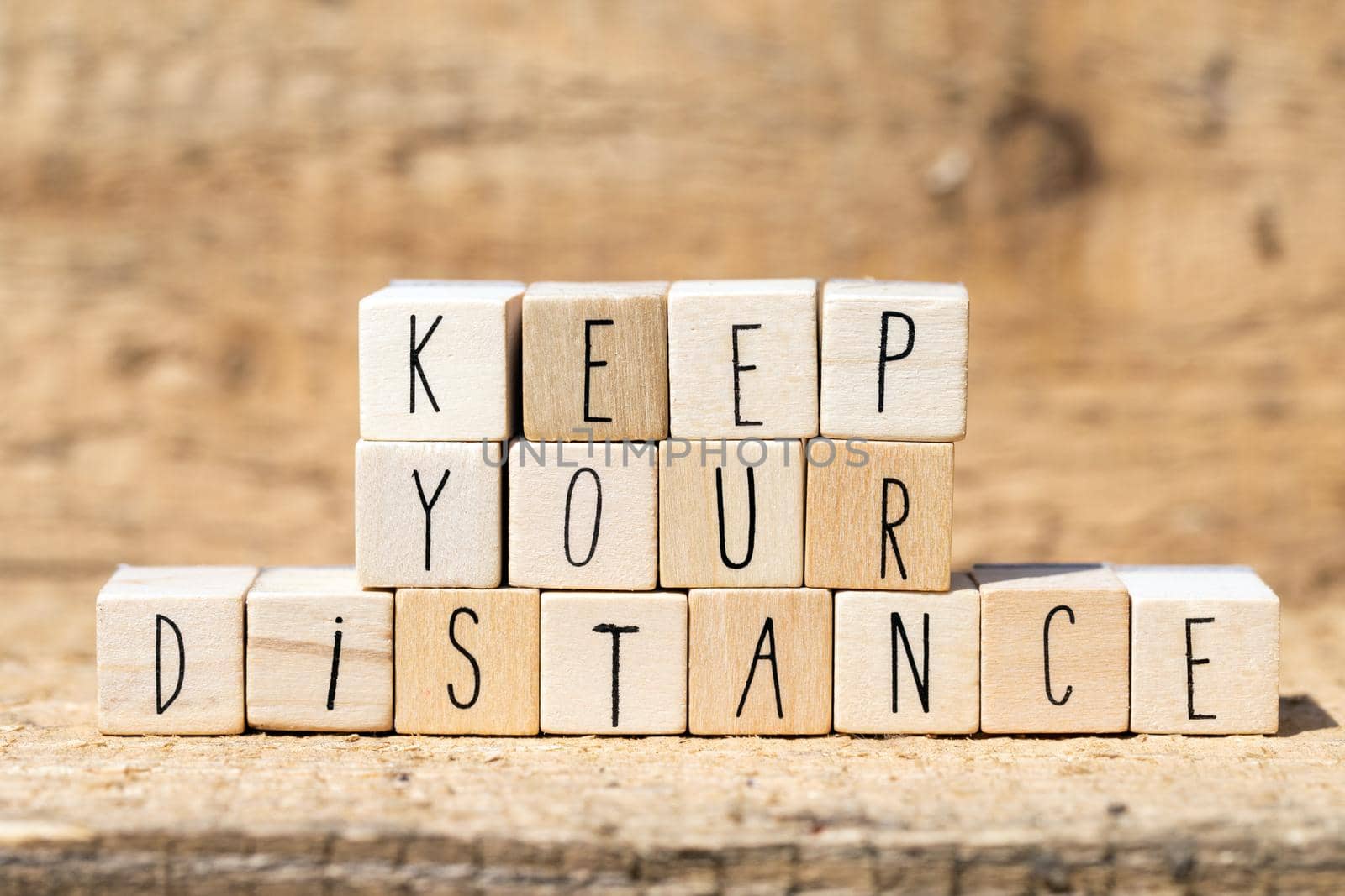 Wooden cubes with the words Keep Your Distance for Coronavirus and social distancing. wooden background closeup